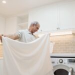 man folding sheets in a laundry room