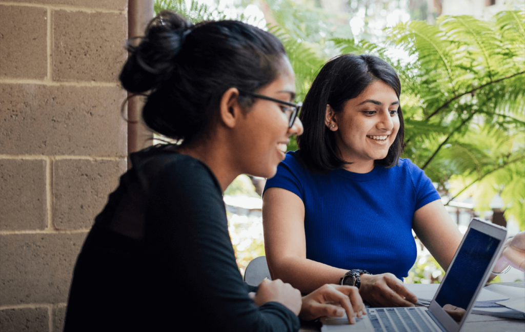 two people working on a laptop outside