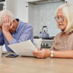 older couple looking at finances and the man is holding his head